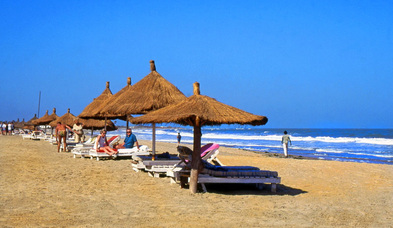 GAMBIA, Kotu Beach, sunbathers and thatched sunshades, near Kombo Beach Hotel, GAM915JPL A 800