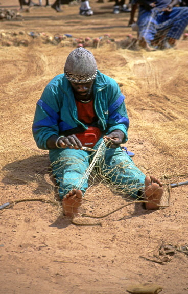 GAMBIA, fishing village, fisherman mending net, GAM992JPL A  575 deep