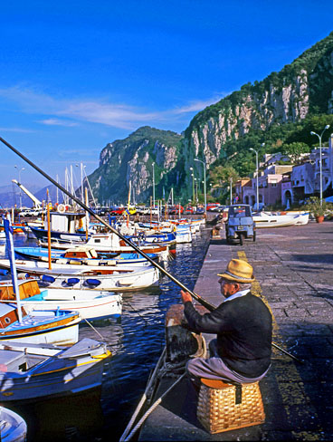 ITALY, Campania, Amalfi Coast, CAPRI, fishing boats along Marina Grande, man fishing, ITL959JPL  488 deep