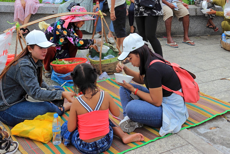 CAMBODIA, Phnom Penh, street food, people enjoying food bought from vendor, CAM2097JPL A 770
