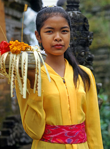 Indonesia, BALI, village girl at temple, with flower offerings, BAL546JPL A 495 deep